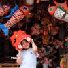 Em nhỏ thích thú đội đầu lân giữa không gian rực rỡ của đèn cá chép, mặt nạ và đồ chơi Trung thu truyền thống. (Ảnh: Phạm Tuấn Anh/TTXVN)