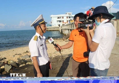 Các phóng viên Thắng Trung (cầm mic) và Sỹ Tuyên (TTXVN) quay phỏng vấn cán bộ hải quân trực tiếp làm nhiệm vụ canh gác bảo vệ trên đảo Đá Thị, Trường Sa hồi tháng 4/2021. (Ảnh: Phan Sáu/TTXVN)