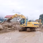 Các phương tiện máy móc tập trung san gạt cây cối, đất đá góp phần thông đường tạm thời cho nhân dân đi lại. (Ảnh: Quý Trung/TTXVN)