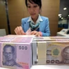 Nhân viên ngân hàng kiểm đếm đồng baht tại Bangkok, Thái Lan. (Ảnh: AFP/TTXVN)