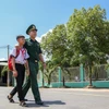 Em Huỳnh Văn Vương được Trung úy Nguyễn Đình Đức, Đội trưởng Đội Vận động Quần chúng Đồn Biên phòng Tống Lê Chân, đưa đến lớp. (Ảnh: Giang Phương/TTXVN)