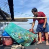 Ngư dân Võ Quốc Nguyện, thuyền trưởng tàu cá PY-90945 thực hiện việc đem rác thải về bờ sau mỗi chuyến biển. (Ảnh: Tường Quân/TTXVN)