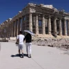 Du khách che ô tránh nắng nóng khi tham quan thành cổ Acropolis ở Athens, Hy Lạp, ngày 16/7. (Ảnh: Getty Images/TTXVN)