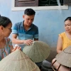 Anh Nguyễn Thanh Thảo trao đổi với những người thợ làng nón truyền thống Đốc Sơ (Huế) về sản phẩm nón sen. (Ảnh: Minh Quyết/TTXVN)