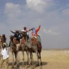 Khách du lịch cưỡi lạc đà khi tham quan quần thể Kim tự tháp Giza ở ngoại ô Cairo (Ai Cập). (Ảnh: AFP/TTXVN)