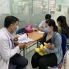 Phụ huynh đưa trẻ đi tiêm vaccine phòng bệnh sởi. (Ảnh: Đinh Hằng/TTXVN)