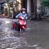 Người dân phải dắt xe bị chết máy qua dòng nước ngập trên đường Phú Thuận (Quận 7). (Ảnh: TTXVN phát)