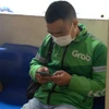 Anh Nguyễn Đức Nghiêm mệt mỏi chờ đợi xác minh lý lịch tư pháp để đăng ký chạy xe ôm công nghệ. (Ảnh: Lê Đức/Vietnam+)