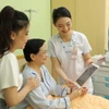 Nhân viên y tế Bệnh viện Đại học Y dược Thành phố Hồ Chí Minh sử dụng máy tính bảng cập nhật và chia sẻ thông tin với người bệnh. (Ảnh: TTXVN phát)