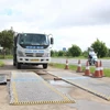 Lực lượng chức năng điều tiết phương tiện vào khu vực cân kiểm tra tải trọng. (Ảnh: Nguyễn Hằng/TTXVN)