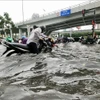 Nước ngập đến hơn nửa mét khiến người dân TP Hồ Chí Minh di chuyển hết sức khó khăn. (Nguồn: TTXVN)