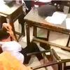 Nam sinh bị ba học sinh đánh hội đồng ngay trong lớp và phải ôm đầu chịu trận. (Ảnh cắt từ clip)