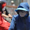 Người ra đường lúc quá nắng nóng nên bôi kem chống nắng, mặc quần áo chống nắng, đội mũ rộng vành, đeo kính râm để tránh sốc nhiệt. (Ảnh: Hoàng Hiếu/TTXVN)