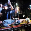 Ngư dân Nguyễn Ngọc được các lực lượng và gia đình hỗ trợ đưa đi bệnh viện cấp cứu, điều trị. (Ảnh: TTXVN phát)