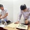 Thực hiện công đoạn in tranh trên giấy Dó. (Ảnh: Minh Ngọc/TTXVN phát)