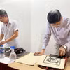 Thực hiện công đoạn in tranh trên giấy Dó. (Ảnh: Minh Ngọc/TTXVN phát)