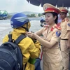 Cảnh sát Giao thông cấp phát mũ bảo hiểm đạt chuẩn cho người dân. (Ảnh: TTXVN phát)