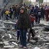 Người dân Palestine bên đống đổ nát của những tòa nhà bị phá hủy sau các cuộc không kích của Israel tại thành phố Rafah, Dải Gaza. (Ảnh: THX/TTXVN)