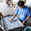 Nghệ nhân Nalongkone Khounphachansi, chủ cơ sở làm giấy Saa tại bản Xienglek, tỉnh Luang Prabang, trang trí hoa lá lên khuôn giấy. (Ảnh: Phạm Kiên/TTXVN) 