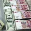 Nhân viên kiểm đồng USD (trái) và đồng nhân dân tệ tại một ngân hàng ở tỉnh An Huy, Trung Quốc. (Ảnh: AFP/TTXVN)
