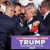 Cựu Tổng thống Donald Trump được mật vụ Mỹ hộ tống rời khỏi bục diễn thuyết trong cuộc vận động tranh cử ở thành phố Butler, bang Pennsylvania sau khi xảy ra vụ nổ súng, ngày 13/7. (Ảnh: IRNA/TTXVN)