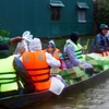 Dùng thuyền vận chuyển nhu yếu phẩm, nước sạch đến người dân các vùng thấp trũng còn bị ngập nước của huyện Lệ Thủy (Quảng Bình). (Ảnh: Tá Chuyên/TTXVN)