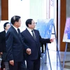 Thủ tướng Phạm Minh Chính giới thiệu với Tổng Bí thư, Chủ tịch nước Lào Thongloun Sisoulith một số hình ảnh về hoạt động đối ngoại của Tổng Bí thư Nguyễn Phú Trọng. (Ảnh: Dương Giang/TTXVN)