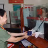 Cán bộ Phòng Quản lý xuất nhập cảnh, Công an tỉnh Hà Nam, trao trả hộ chiếu cho công dân. (Ảnh: Thanh Tuấn/ TTXVN)