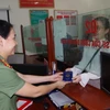Cán bộ Phòng Quản lý xuất nhập cảnh, Công an tỉnh Hà Nam, trao trả hộ chiếu cho công dân. (Ảnh: Thanh Tuấn/ TTXVN)