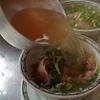 Nước dùng của phở phải trong, nóng, chan vào bát phải đủ để làm dậy lên hương vị của bánh phở, rau thơm, hành và thịt. (Ảnh: Ngọc Liên/TTXVN)