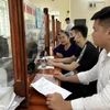 Người dân thực hiện thủ tục hành chính tại Bộ phận tiếp nhận và trả kết quả thủ tục hành chính. (Ảnh: TTXVN phát)