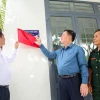 Trưởng Ban Tuyên giáo Trung ương Nguyễn Trọng Nghĩa (giữa) và ông Vũ Mạnh Hùng, Chủ tịch HĐQT - Tổng giám đốc Tập đoàn Hùng Nhơn thực hiện nghi thức mở bảng nhà, trao nhà tình nghĩa cho cựu chiến binh Dương Thị Thu Sương. (Ảnh: Giang Phương/TTXVN)