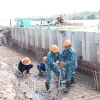 Thi công các hạng mục kè chống sạt lở bờ sông Giao Hòa. (Ảnh Công Trí/TTXVN)