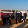 Người Palestine xếp hàng lấy nước sinh hoạt tại khu lều tạm ở Dải Gaza, ngày 16/1/2024. (Ảnh: AFP/TTXVN)