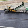 Nhà thầu Tổng Công ty Vinaconex thi công thảm bêtông nhựa mặt đường tại nút giao quốc lộ 8A, xã Thanh Bình Thịnh, huyện Đức Thọ. (Ảnh: Hữu Quyết/TTXVN)