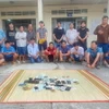 Các đối tượng tham gia đá gà qua mạng cùng tang vật tại cơ quan Công an. (Ảnh: TTXVN phát)