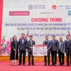 Ông Phạm Đức Ấn - Chủ tịch Hội đồng thành viên Agribank trao tặng quà của Agribank hỗ trợ hộ cận nghèo, đối tượng chính sách quận Hà Đông (Hà Nội) nhân dịp Tết Nguyên đán Giáp Thìn. (Ảnh: PV/Vietnam+)