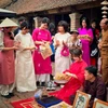 Du khách nghe giới thiệu và trực tiếp trải nghiệm làm tranh Đồng Hồ. (Ảnh: Mai Mai/Vietnam+)