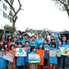 Các em học sinh chụp ảnh cùng anh chị tình nguyện viên người Mỹ. (Ảnh: PV/Vietnam+)