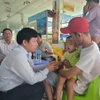 Tiến sỹ Lê Quang Trí, Giám đốc Sở Giáo dục và Đào tạo tỉnh Tiền Giang (trái) thăm hỏi cháu bé vừa được giải cứu. (Ảnh: Minh Trí/TTXVN)