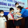 Lãnh đạo Đoàn thanh niên Thành phố Hồ Chí Minh cùng các mạnh thường quân tặng học bổng cho các em học sinh mồ côi do dịch COVID-19. (Ảnh: Thanh Vũ/TTXVN)