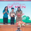 Phó Tổng giám đốc Thông tấn xã Việt Nam Nguyễn Thị Sự (trái) trao giải Khát vọng Dế Mèn cho tác giả Lê Sinh Hùng (giữa). (Ảnh: Minh Quyết/TTXVN)