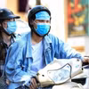 Đôi bạn trẻ dùng khẩu trang đeo lên trán để tránh cái nắng gay gắt. (Ảnh: Thành Đạt/TTXVN)