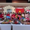 Đại sứ Nguyễn Thị Bích Thảo cùng cán bộ, nhân viên Đại sứ quán tại gian hàng của Việt Nam tham gia hội chợ. (Ảnh: TTXVN phát)
