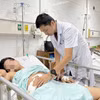 Bác sĩ thăm khám cho người bệnh sau phẫu thuật. (Ảnh: PV/Vietnam+)