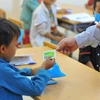Nhân viên y tế cấp phát thuốc uống phòng dịch bạch hầu cho học sinh. (Ảnh: Hoàng Hiếu/TTXVN)