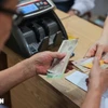 Người dân nhận tiền tại điểm chi trả Nhà văn hóa khu dân cư số 3A-3B Thanh Lương, quận Hai Bà Trưng, Hà Nội. (Ảnh: Hoàng Hiếu/TTXVN)