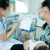 Nhân viên y tế hướng dẫn người dân về vaccine trước khi tiêm cho trẻ. (Ảnh: Minh Quyết/TTXVN) 