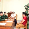 Lực lượng biên phòng lấy lời khai hai đối tượng. (Ảnh TTXVN phát)