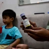 Một phụ huynh cầm chai thuốc ho con trai anh sử dụng dẫn đến tổn thương thận cấp tính tại Jakarta, Indonesia, ngày 11/2/2023. (Ảnh: AFP/TTXVN)